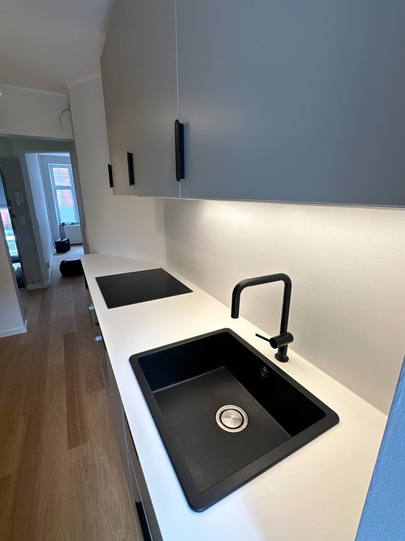 Nyt køkken med hvid bordplade og sort vask