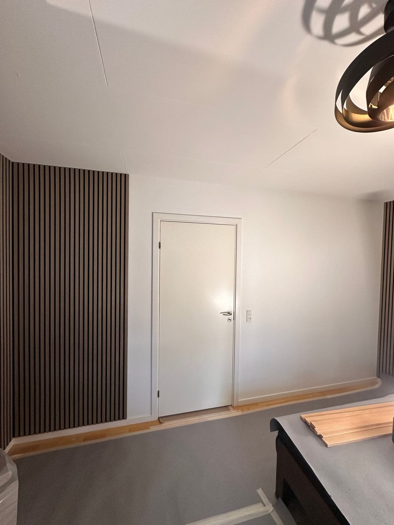 Væg med mørke trælameller og hvid dør